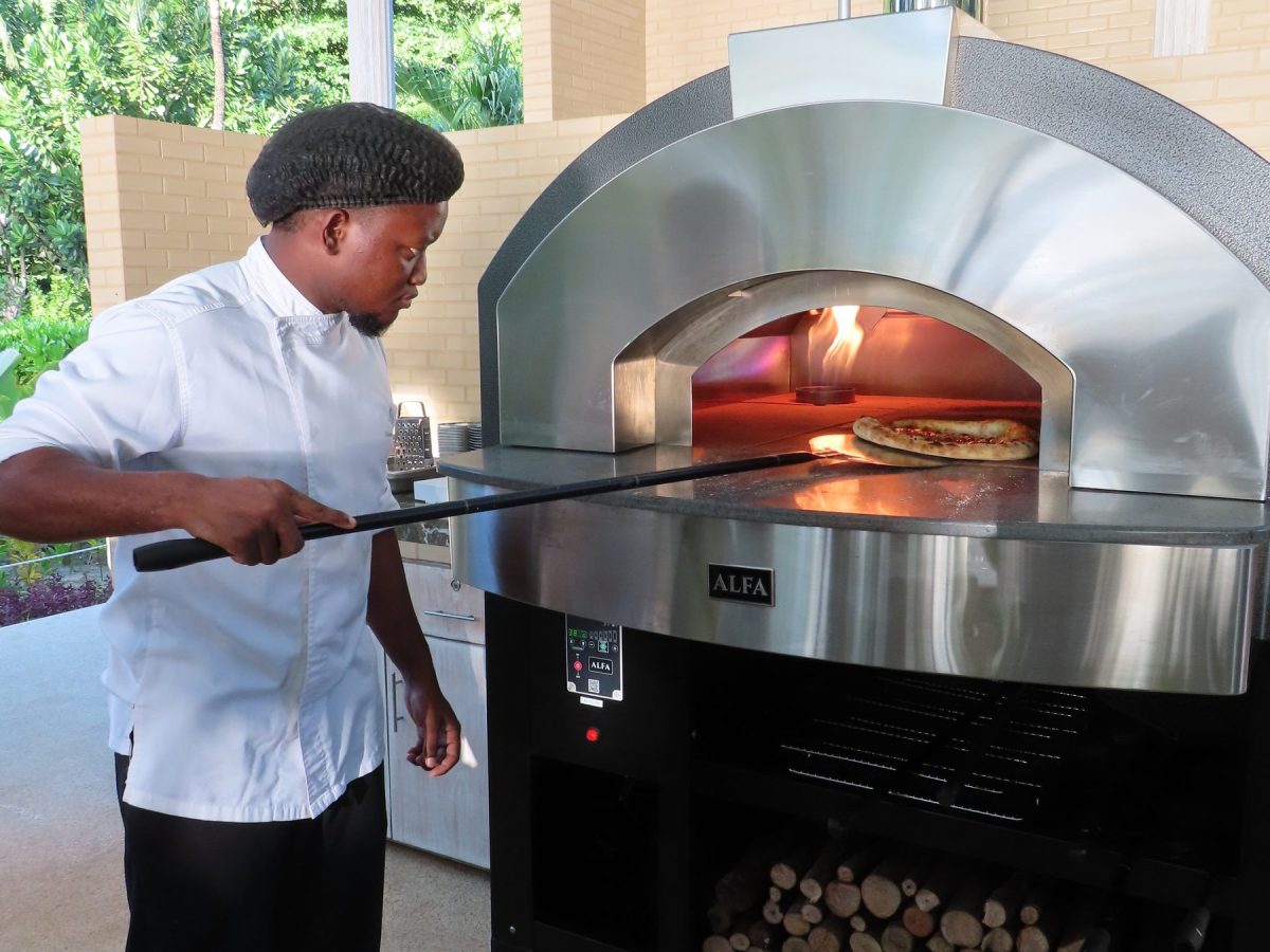 Chef loading a pizza into the wood-fired oven at Kannel Pizzeria, Four Seasons Mahe